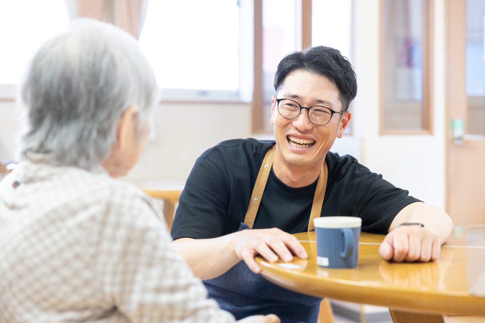 テーブルを挟んで入居者と笑顔で話すスタッフ