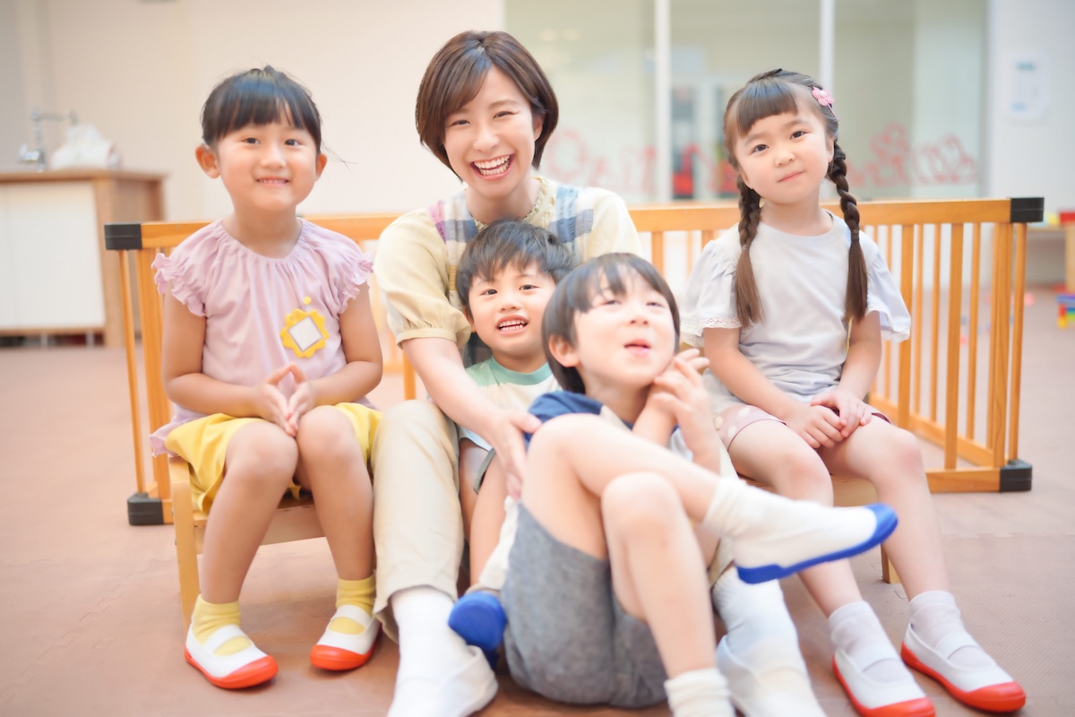 スタッフを囲んで座り、笑顔を見せる子どもたち