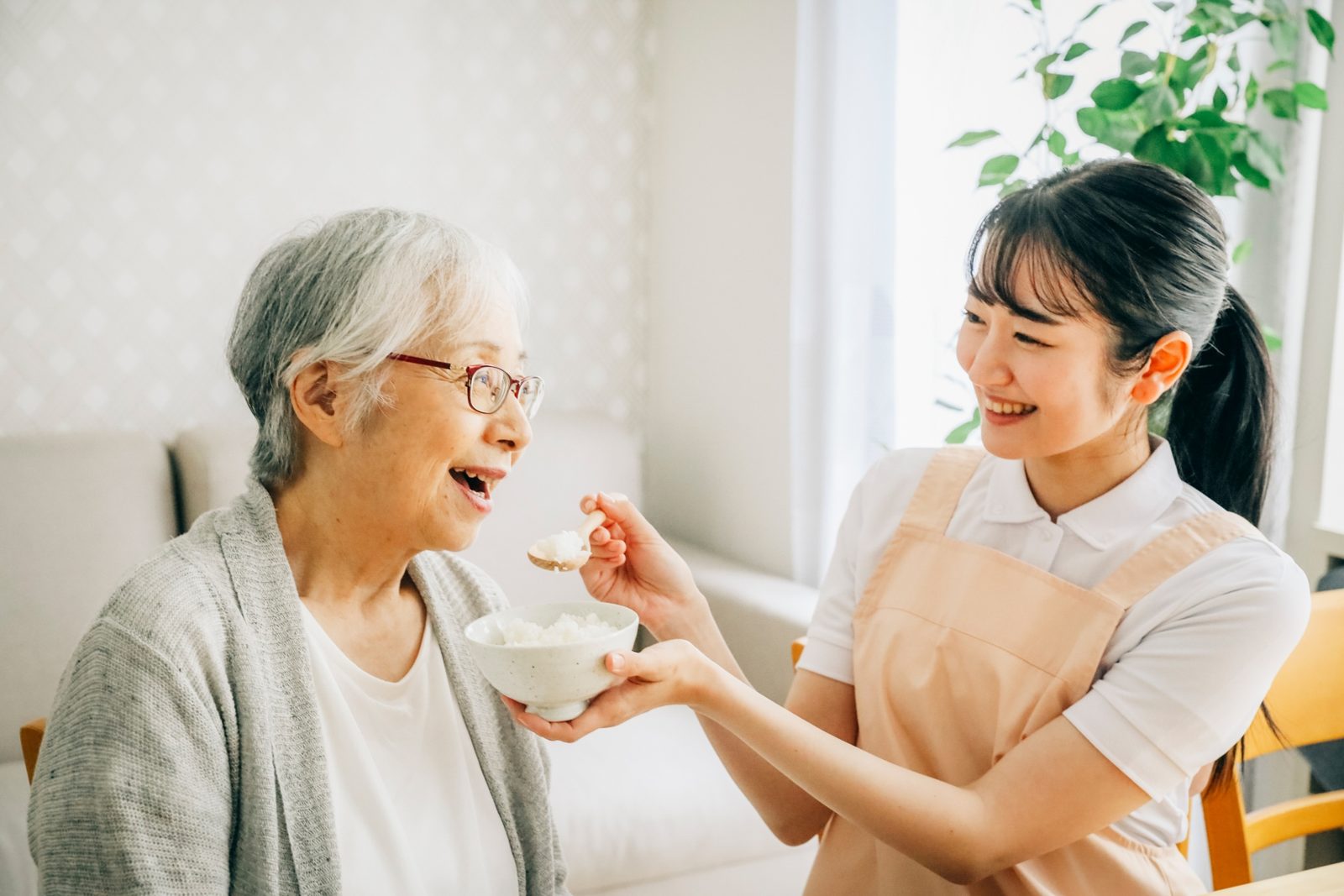 高齢の女性の食事をスプーンで介助するスタッフ
